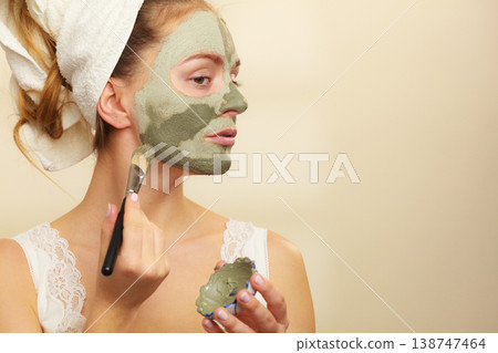 Woman applying with brush clay mud mask to her face Woman applying with brush clay mud mask to her face 138747464