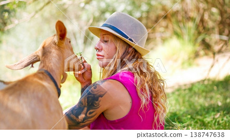Woman feeding a goat a small branch outdoors Woman feeding a goat a small branch outdoors 138747638