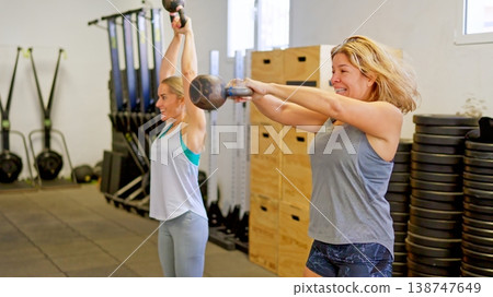 Women training with kettlebells performing strength exercises in gym Women training with kettlebells performing strength exercises in gym 138747649