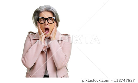Senior woman with glasses and pink jacket reacting to noise Senior woman with glasses and pink jacket reacting to noise 138747657