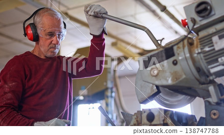 Senior carpenter working with saw wearing safety gear Senior carpenter working with saw wearing safety gear 138747788