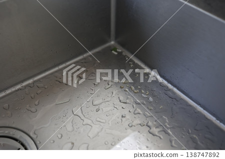 Kitchen sink, food scraps and water droplets on the countertop, close-up. Kitchen sink, food scraps and water droplets on the countertop, close-up. 138747892