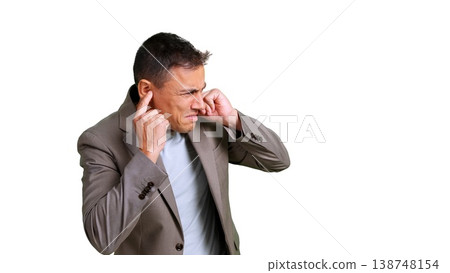 Man plugging ears with fingers to block out loud, bothersome sound 138748154