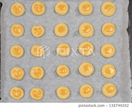 Raw orange and lemon curd thumbprint cookies on a baking sheet Raw orange and lemon curd thumbprint cookies on a baking sheet 138749202