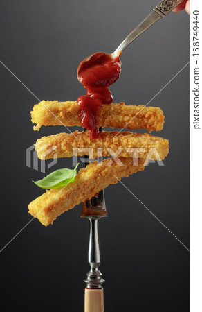 Fish fingers with basil and ketchup on a fork. 138749440