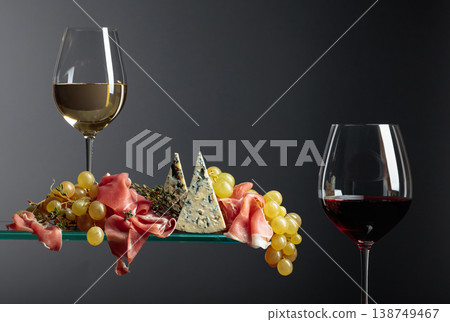 Glasses of red and white wine with snacks. Grapes with blue cheese, prosciutto and thyme. 138749467