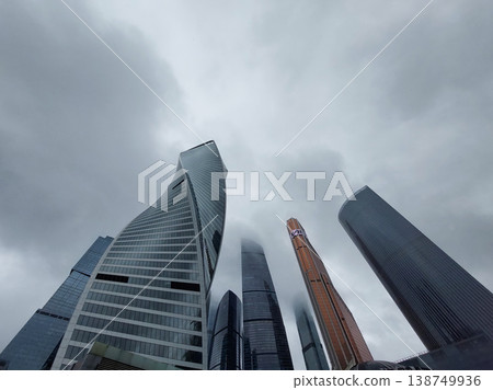 Low-angle view of high-rise city buildings under gray clouds 138749936