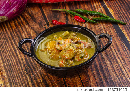 Thai green curry with shrimp and broccoli in a bowl, surrounded by fresh ingredients on a wooden table Thai green curry with shrimp and broccoli in a bowl, surrounded by fresh ingredients on a wooden table 138751025