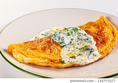 Golden yellow omelette with creamy herb sauce served on a plate, isolated on white background. Golden yellow omelette with creamy herb sauce served on a plate, isolated on white background. 138751027