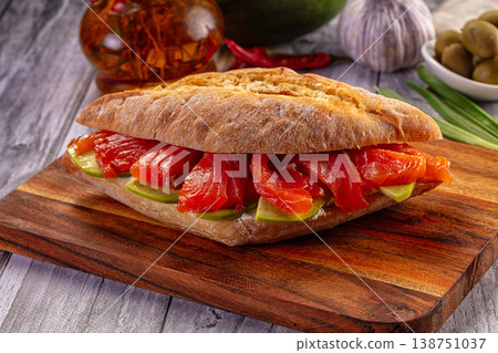 Gourmet smoked salmon and avocado ciabatta sandwich on a rustic wooden board. Gourmet smoked salmon and avocado ciabatta sandwich on a rustic wooden board. 138751037