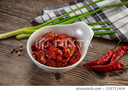 Spicy red chili pickle in a white bowl on a rustic wooden table with fresh ingredients Spicy red chili pickle in a white bowl on a rustic wooden table with fresh ingredients 138751404