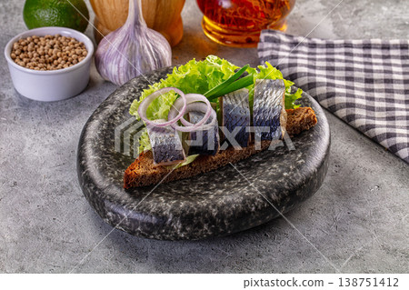 Rustic open-faced sandwich with salted herring, onion, and lettuce on dark rye bread Rustic open-faced sandwich with salted herring, onion, and lettuce on dark rye bread 138751412