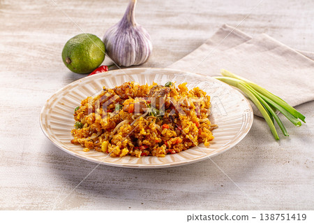 Savory fried rice with meat and vegetables served on a plate with fresh ingredients Savory fried rice with meat and vegetables served on a plate with fresh ingredients 138751419