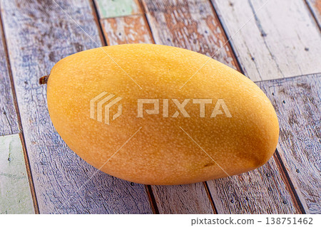 Fresh ripe yellow mango fruit on a rustic distressed wood table background. Fresh ripe yellow mango fruit on a rustic distressed wood table background. 138751462