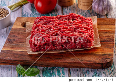 Fresh minced meat on a cutting board with tomatoes, garlic, and basil. Fresh minced meat on a cutting board with tomatoes, garlic, and basil. 138751471