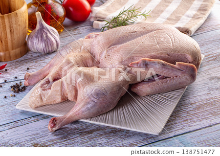Raw whole duck on a plate with fresh herbs and vegetables for cooking on a wooden table 138751477