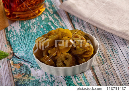 Sliced pickled jalapeno peppers in a white bowl on a rustic wooden table Sliced pickled jalapeno peppers in a white bowl on a rustic wooden table 138751487