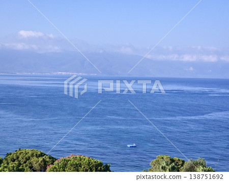 Picturesque view to blue sea and mountain island on horizon in mist. Calm water surface, background for traveling and vacation,Beautiful sea view, sailboats far away in the sea in sunny day. 138751692