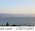 Picturesque view to blue sea and mountain island on horizon in mist. Calm water surface, background for traveling and vacation,Beautiful sea view, sailboats far away in the sea in sunny day. 138751697