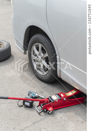 Changing the tire on a car lifted with a jack. 138751845