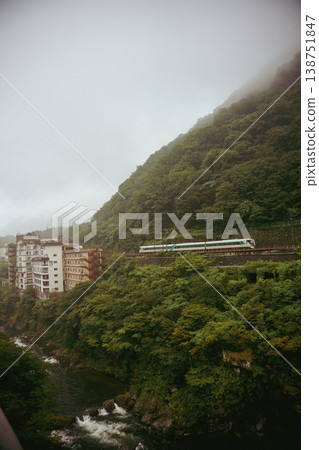 A misty valley, a train and a ryokan (Japanese inn). A misty valley, a train and a ryokan (Japanese inn). 138751847