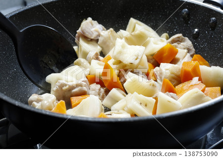 Chicken thighs and root vegetables cooking in a deep frying pan. 138753090