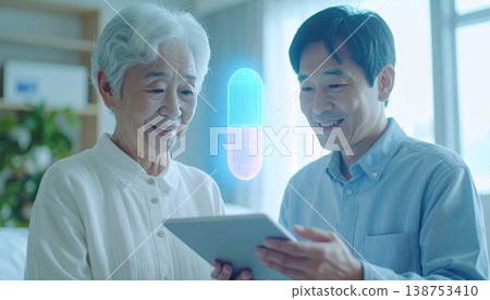一位老婦人和她的兒子使用平板電腦管理他們的健康，藥物的全像圖漂浮在空中。 138753410