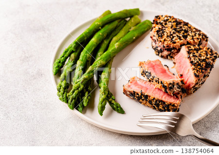 Tuna steak fried in sesame seeds served with asparagus. Tuna steak fried in sesame seeds served with asparagus. 138754064