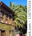 Traditional wooden house exterior with large palm trees and clear blue sky in a sunny residential area 138755058