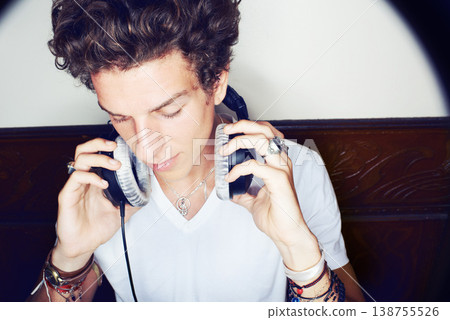 Man with headphones, rock dj and audio beats with rockstar attitude on white background with spotlight. Cool punk style, grunge sound and music, club culture with male model listening to earphones. 138755526