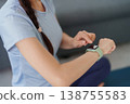 Adult Asian woman tracking fitness data on modern smartwatch checking health monitoring app wearing athletic clothing at home for well-being 138755583