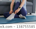 Asian adult woman preparing yoga exercise at home adjusting sport sock on mat healthy lifestyle wellness fitness routine self care indoor activity morning relaxation 138755585