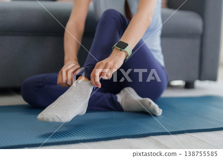 Asian adult woman preparing yoga exercise at home adjusting sport sock on mat healthy lifestyle wellness fitness routine self care indoor activity morning relaxation Asian adult woman preparing yoga exercise at home adjusting sport sock on mat healthy lifestyle wellness fitness routine self care indoor activity morning relaxation 138755585