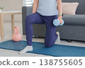 Adult Asian woman home workout strength training using dumbbell practicing lunge exercise at living room floor for fitness health body muscle gain 138755605