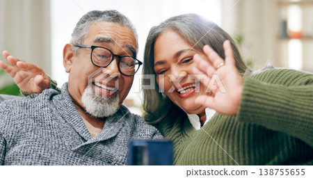Senior couple, video call and phone on sofa with wave hello, smile and communication on web in home living room. Elderly lady, old man and happy for contact, live streaming and chat on social media 138755655