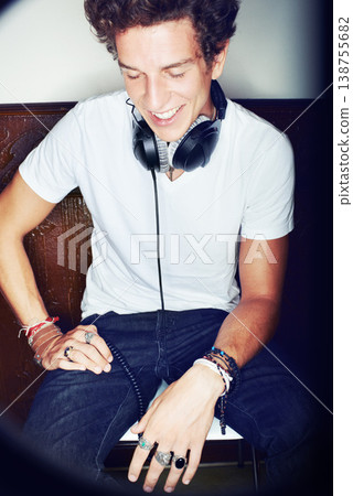 Man with headphones, smile and dj with fun attitude spotlight or laughing and sitting. Cool punk style, grunge sound and rock music mix, club culture with happy male model listening for entertainment 138755682