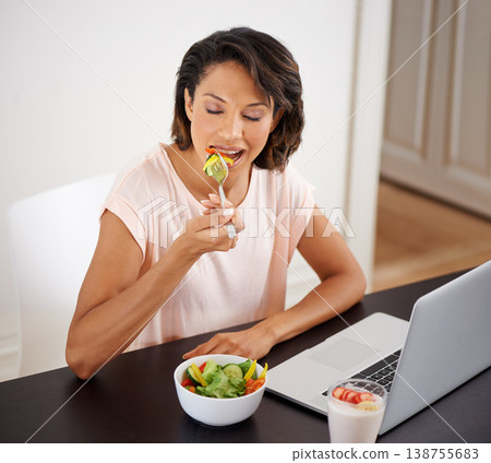 Eating, salad and woman with laptop, remote work and healthy food or nutrition in home office. Hungry, person and working on lunch break with fruit and vegetables for energy or wellness in house 138755683
