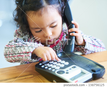 Playing, dial and a child on a telephone phone call for communication in a house. Home, contact and a girl, kid or baby speaking on a landline for conversation, play or a discussion at a desk Playing, dial and a child on a telephone phone call for communication in a house. Home, contact and a girl, kid or baby speaking on a landline for conversation, play or a discussion at a desk 138756125