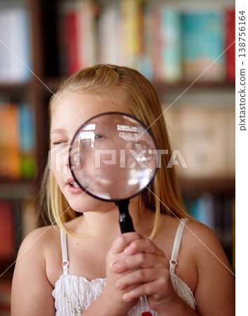 Search, portrait and a child with a magnifying glass in a library for education, learning or inspection. Looking, young detective and a girl, kid or student with equipment for studying or attention 138756164