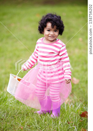 Portrait, happy child and tutu on grass in park with basket for leaves for autumn. Little girl, pink clothes and curly hair with rain boots for growth, development and changing of season for Easter Portrait, happy child and tutu on grass in park with basket for leaves for autumn. Little girl, pink clothes and curly hair with rain boots for growth, development and changing of season for Easter 138756202