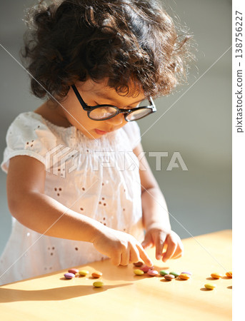 Toddler, counting and sweets for learning math, equation or childhood development knowledge. Girl, glasses and candy on table for intelligence growth or education homework, preschool or study reward Toddler, counting and sweets for learning math, equation or childhood development knowledge. Girl, glasses and candy on table for intelligence growth or education homework, preschool or study reward 138756227