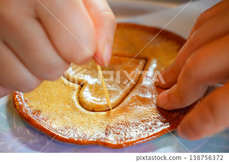 Child's Hands Carefully Carving Heart Shaped Dalgona Candy with a Toothpick in Korea Child's Hands Carefully Carving Heart Shaped Dalgona Candy with a Toothpick in Korea 138756372