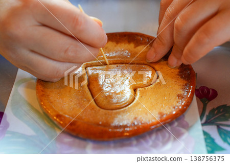 Child's Hands Carefully Carving Heart Shaped Dalgona Candy with a Toothpick in Korea 138756375