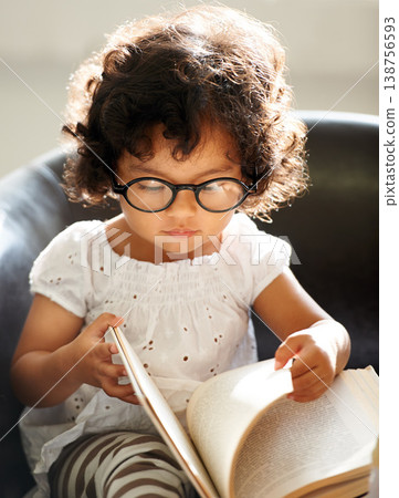 Baby, sofa and a child reading a book for education, learning and knowledge in a house. Morning, smart and a girl, kid or toddler with a story and glasses for studying or childhood on the couch 138756593