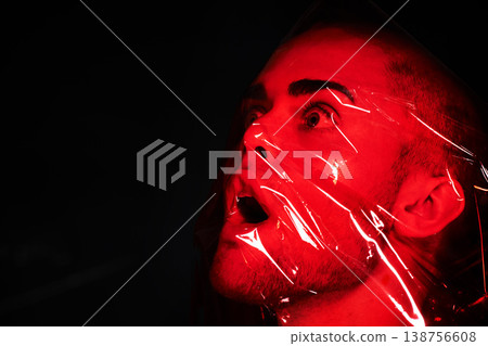 Man, red plastic and suffocate in studio isolated on a black background mockup. Polyethylene, film and person with depression, fear and anxiety, stress and mental health crisis, psychology and neon 138756608