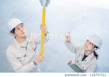 A man and a woman in work clothes inspecting an automatic fire alarm system. A man and a woman in work clothes inspecting an automatic fire alarm system. 138757311