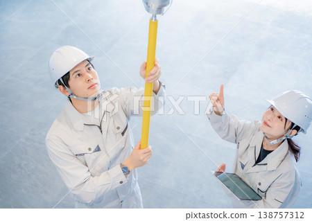 一男一女身穿工作服,正在檢查自動火災警報系統。 一男一女身穿工作服,正在檢查自動火災警報系統。 138757312