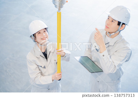 A man and a woman in work clothes inspecting an automatic fire alarm system. A man and a woman in work clothes inspecting an automatic fire alarm system. 138757313
