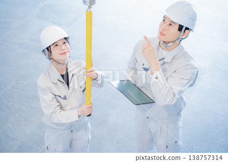 一男一女身穿工作服，正在檢查自動火災警報系統。 138757314