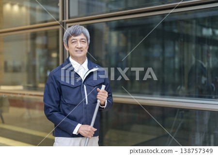 一位六十多歲、身穿工作服的男子對著鏡頭微笑;他是一名建築管理員/設施管理人員。 (圖片) 一位六十多歲、身穿工作服的男子對著鏡頭微笑;他是一名建築管理員/設施管理人員。 (圖片) 138757349